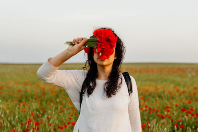 Woman with poppy bouquet covering face