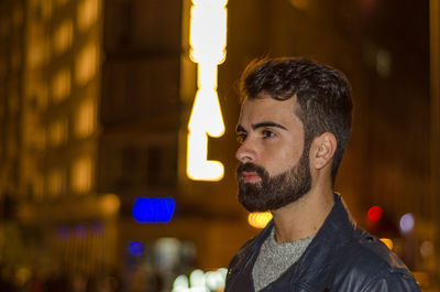 Young man looking away in city at night