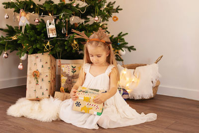 Portrait of girl playing with christmas tree at home