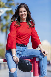 Smiling teenage girl wearing red top in city during sunny day