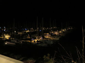 Sailboats moored in harbor at night