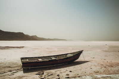 Boat moored on beach against clear sky