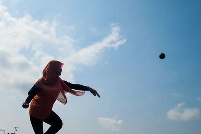 Low angle view of woman playing with ball against sky