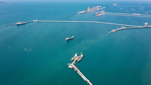 Aerial view oil pipes to oil tanker ships at pier off the coast in beautiful peaceful environment 