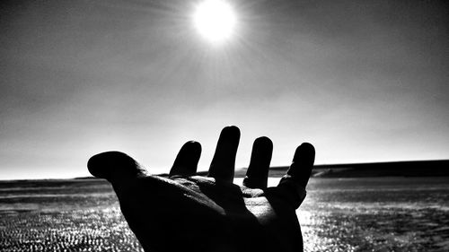 Close-up of hand over sea on sunny day