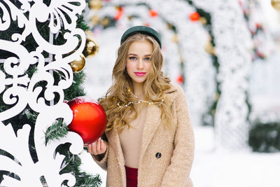 A young stylish woman with a red christmas tree big ball. a festive christmas market 