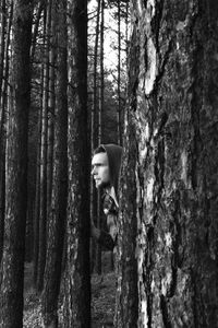 Young man standing amidst trees in forest