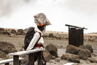 Young man with horse on sand against sky