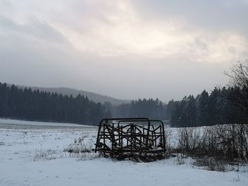 Bicycle on snow covered field against sky