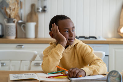 Cute pensive biracial child boy look side at window distracted from study dream about computer game
