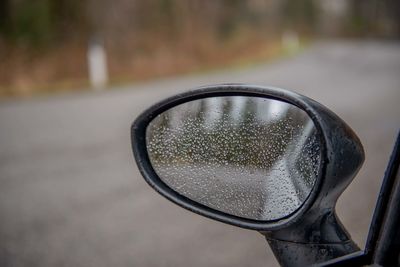 Close-up of raindrops on side-view mirror