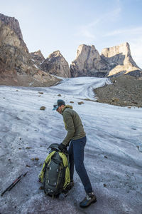 Backpacker packing his bag on glacier below mount asgard.