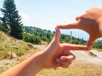 Cropped hand of man against sky