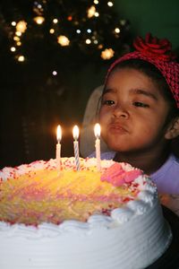 Cute girl blowing birthday candles on cake at home