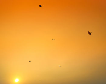 Low angle view of silhouette birds flying against sky during sunset