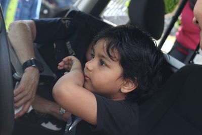 Side view of boy sitting by female police officer in car