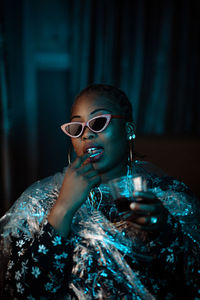 Portrait of young woman wearing sunglasses sitting at home