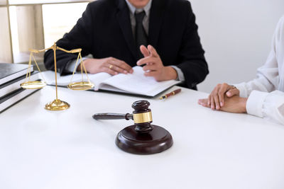 Midsection of lawyer discussing with client on desk