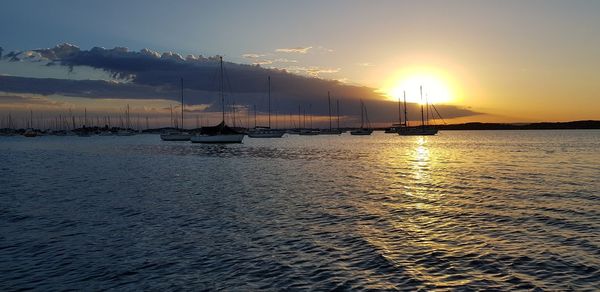 Sailboats in sea against sky during sunset