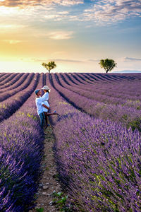 Rear view of woman standing on field against sky during sunset