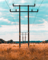 Electricity pylons on land against sky