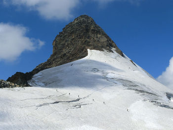 Low angle view of snow covered mountain against blue sky