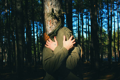 Man covered with coat in forest