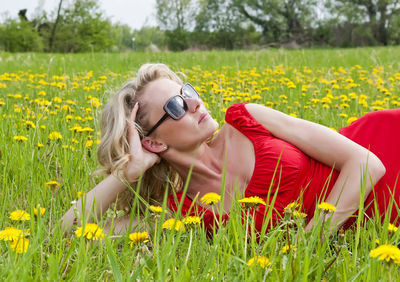 Woman in sunglasses lying on yellow flowering plants