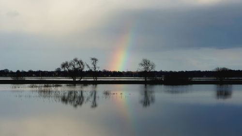 Scenic view of rainbow over lake against sky