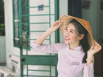 Portrait of smiling young woman standing against building