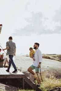 Rear view of teenage boy with father and sister climbing cabin steps