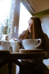 Young woman drinking coffee cup on table