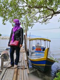 Rear view of woman standing on boat against trees