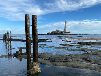 Wooden posts on beach against sky