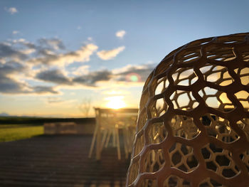 Close-up of electric lamp on field against sky during sunset