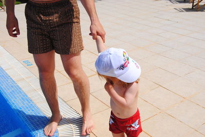 Low section of father with son standing at poolside