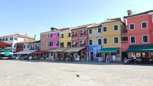 People on street amidst buildings in city against clear sky