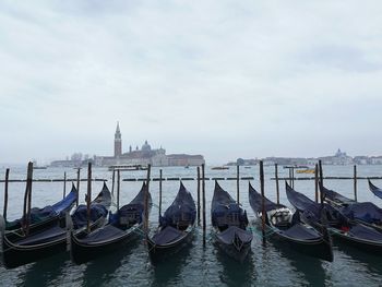 Gondolas moored on grand canal against clear blue sky