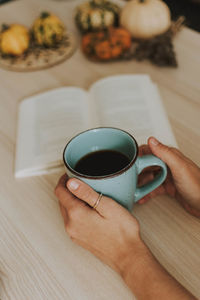 Cropped hands of person holding coffee cup on table