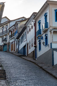 Houses by street in city against sky