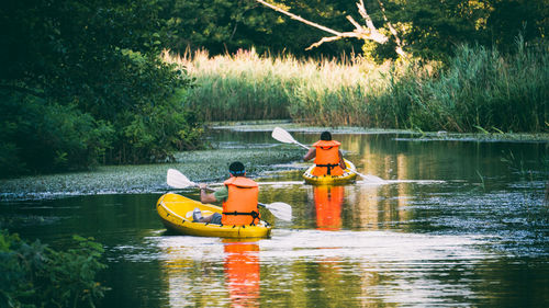Rear view of men sitting on boat in lake