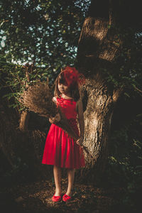 Full length of woman standing by tree trunk