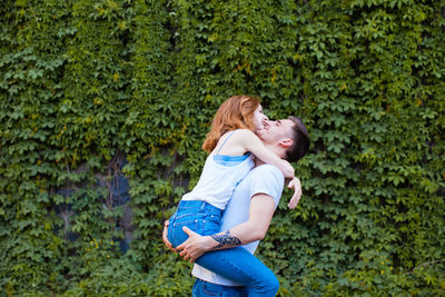 Side view of couple kissing against plants