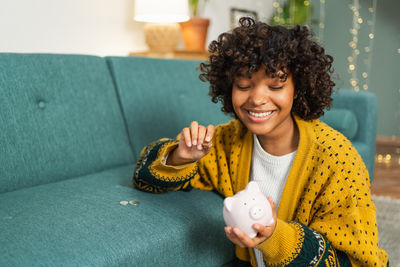 Portrait of young woman sitting on sofa at home