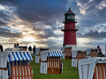 Lighthouse on beach against sky during sunset