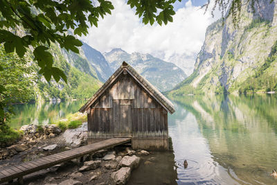 Old wooden boathouse with boardwalk on a pristine alpine lake surrounded by mountains, germany