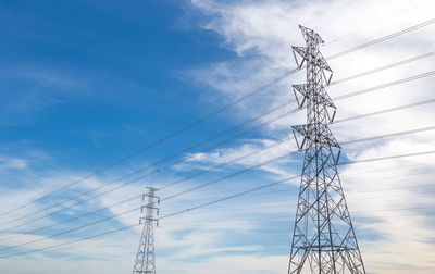 Low angle view of electricity pylon against blue sky