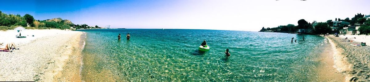Panoramic view of people on beach against clear sky