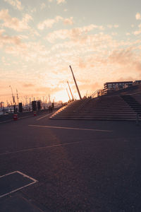 Road by building against sky during sunset