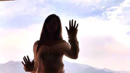 Low angle view of woman standing against sky